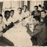 Una decena de hombres sentados a una mesa larga con mantel blanco