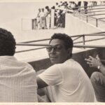 Un hombre con gafas oscuras mira a la cámara desde las gradas
