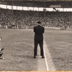 Un hombre de traje, de espaldas sobre la línea, ante un estadio lleno