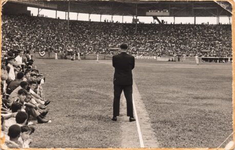 Un hombre de traje, de espaldas sobre la línea, ante un estadio lleno